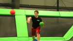 Man Throwing Dodgeball and Holding another in Trampoline Ball Game Area